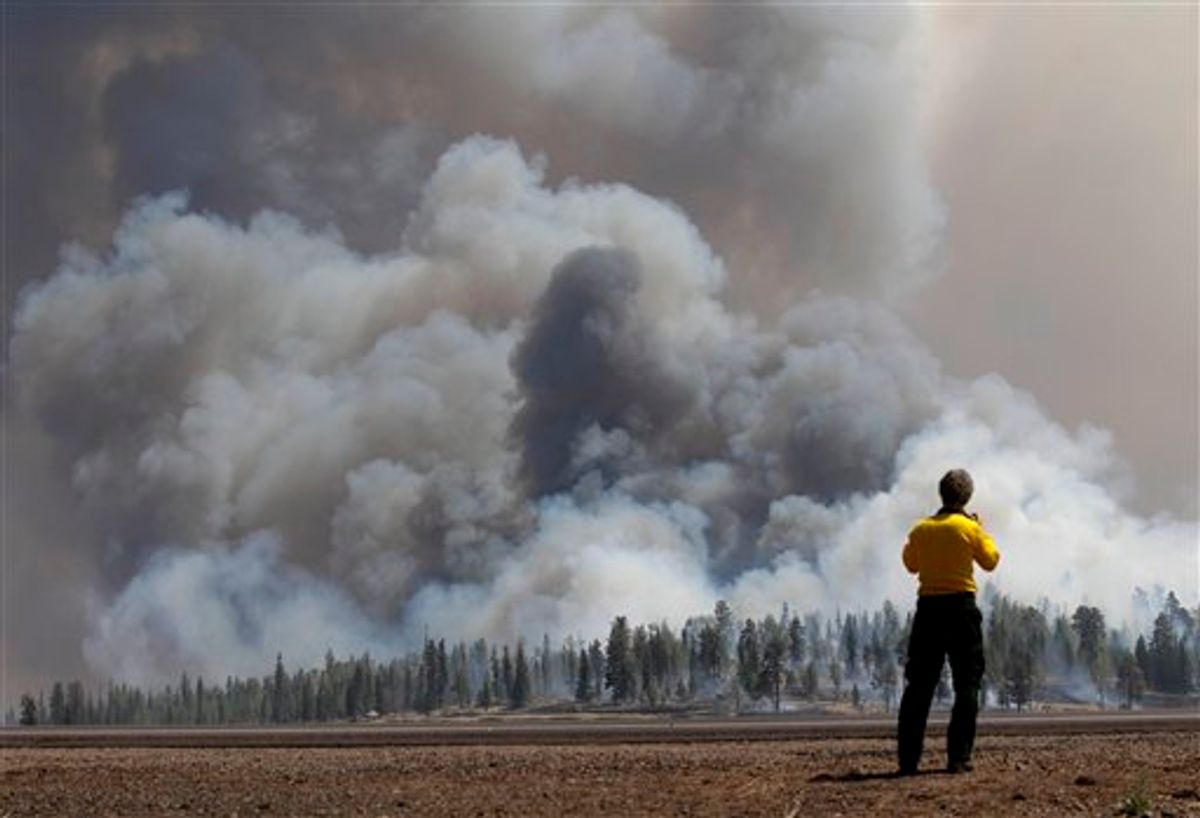 A photographer looks at smoke from a burnout fire as firefighters battle the Wallow Fire in the Apache-Sitgreaves National Forest, Ariz., Sunday, June 12, 2011. Roughly 7,000 residents of two eastern Arizona towns evacuated last week as a wildfire loomed nearby were allowed to return home Sunday as officials expressed confidence that they were making progress in their battle against the huge blaze that has been burning since May. (AP Photo/Jae C. Hong)  (AP)