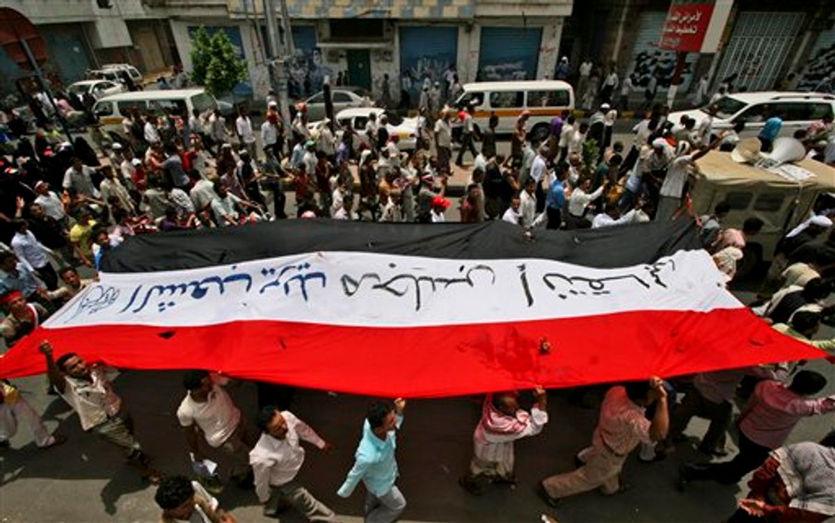 Anti-government protestors hold up their national flag, bearing the words "The people want a transitional council" in Arabic, during a demonstration demanding the resignation of Yemeni President Ali Abdullah Saleh, in Taiz, Yemen, Monday, June 20, 2011. Tens of thousands of Yemenis have taken to the streets of the capital, demanding that the president's son leave the country. Ahmed Saleh, 42, is a one-time heir apparent who commands the elite Yemeni Presidential Guard. The force has been leading the crackdown on pro-democracy demonstrators since the uprising began in February. (AP Photo/Anees Mahyoub) (AP)