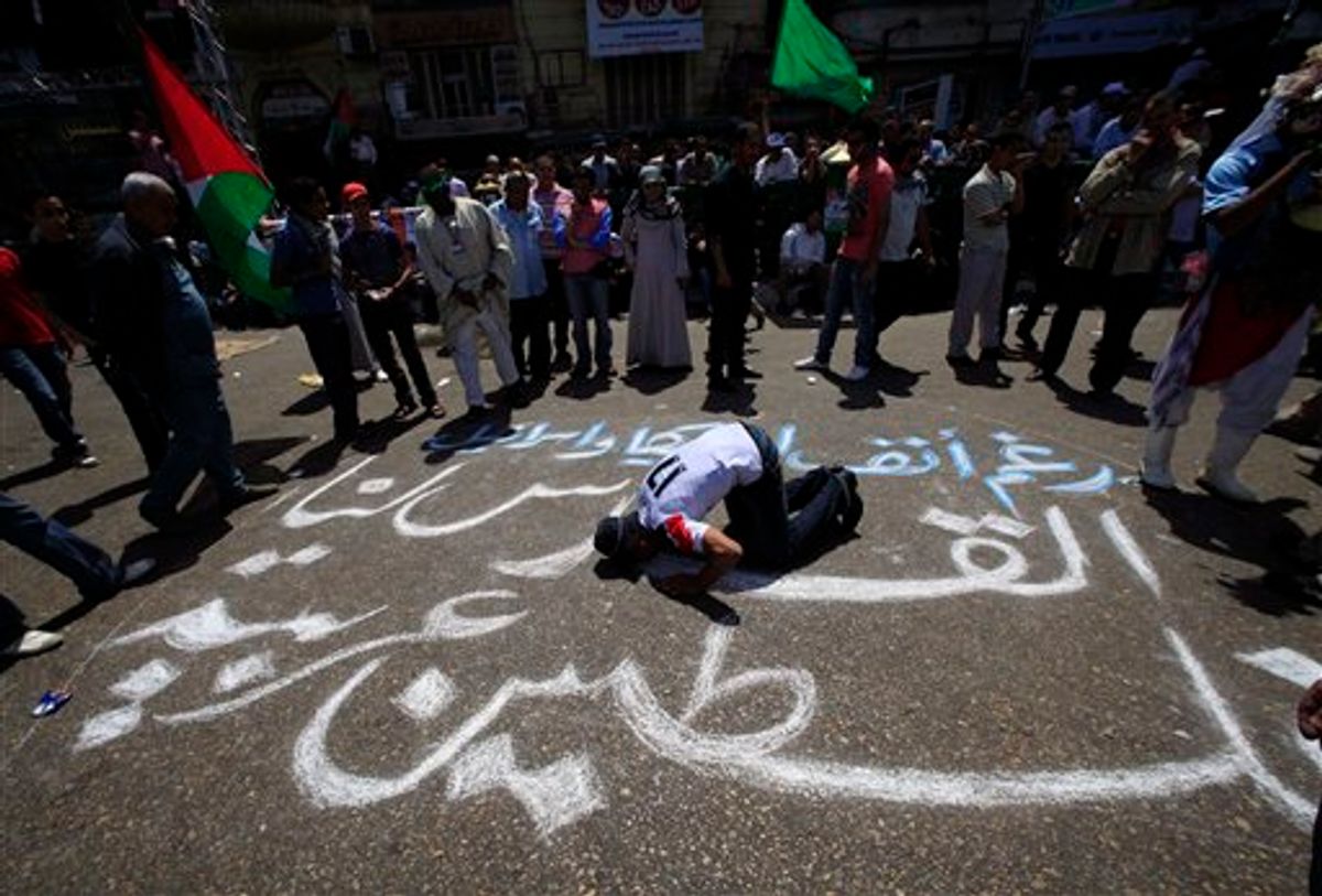 An Egyptian prays on an Arabic slogan reads " Jerusalem for us, Palestine is an Arabic land " during a protest against Israel's closure of Gaza at Tahrir Square, the focal point of Egyptian uprising, in Cairo, Egypt Friday, May 13, 2011. (AP Photo/Amr Nabil) (AP)
