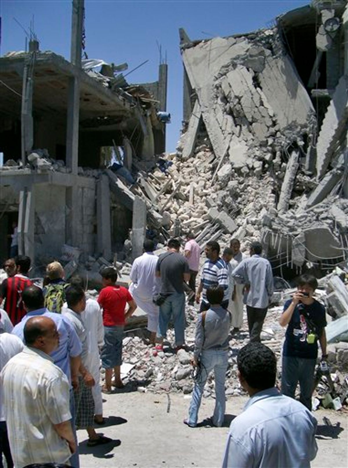 In this photo taken on a government-organized tour, media and others examine the remains of a damaged residential building in Tripoli, Libya, Sunday, June 19, 2011.  The Libyan government accused NATO of bombing a residential neighborhood in the capital and killing civilians early Sunday, adding to its charges that the alliance is striking non-military targets. (AP Photo/Adam Schreck) (AP)