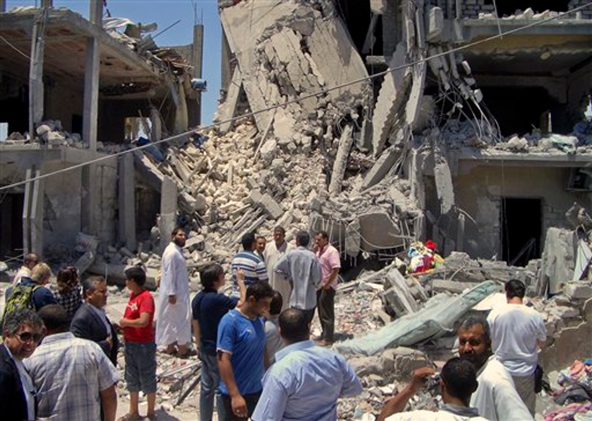 In this photo taken on a government-organized tour, members of the media and others examine the remains of a damaged residential building in Tripoli, Libya Sunday, June 19, 2011