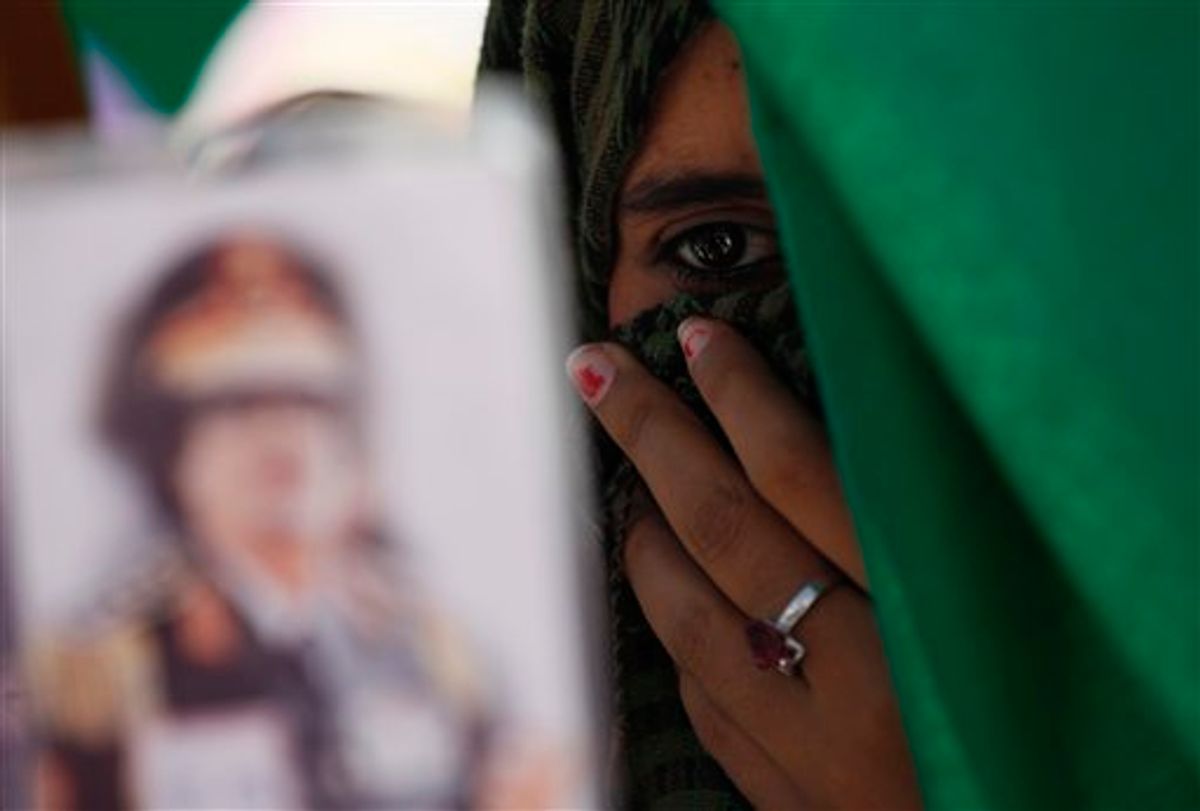 In this photo taken on a government-organized tourm a Libyan student holds a portrait of Libyan leader Moammar Gadhafi, outside the damaged university building in Tripoli, Libya, on Saturday, June 18, 2011. Libyan officials claim that one of the buildings at the university complex was recently hit by a NATO airstrike. (AP Photo/Ivan Sekretarev) (AP)