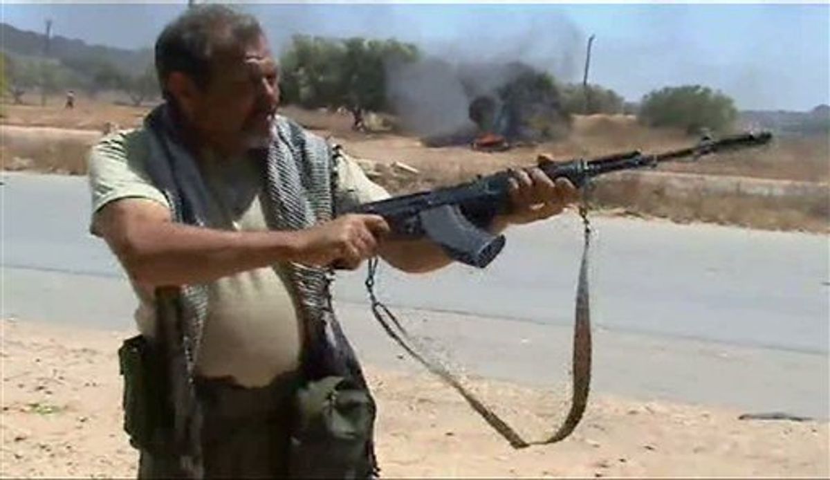 In this image taken from TV, showing rebel forces on the front line as they repel government troops, Sunday June 12, 2011, in Dafniya, Libya. as fighting continued on Sunday near Libya's main port of Misrata, a western redoubt of the rebels.  Video of the battle shows rebels advancing down a road, firing automatic weapons, guns mounted on pick up trucks, rockets and heavy artillery.  (AP Photo/APTN) TV OUT (AP)