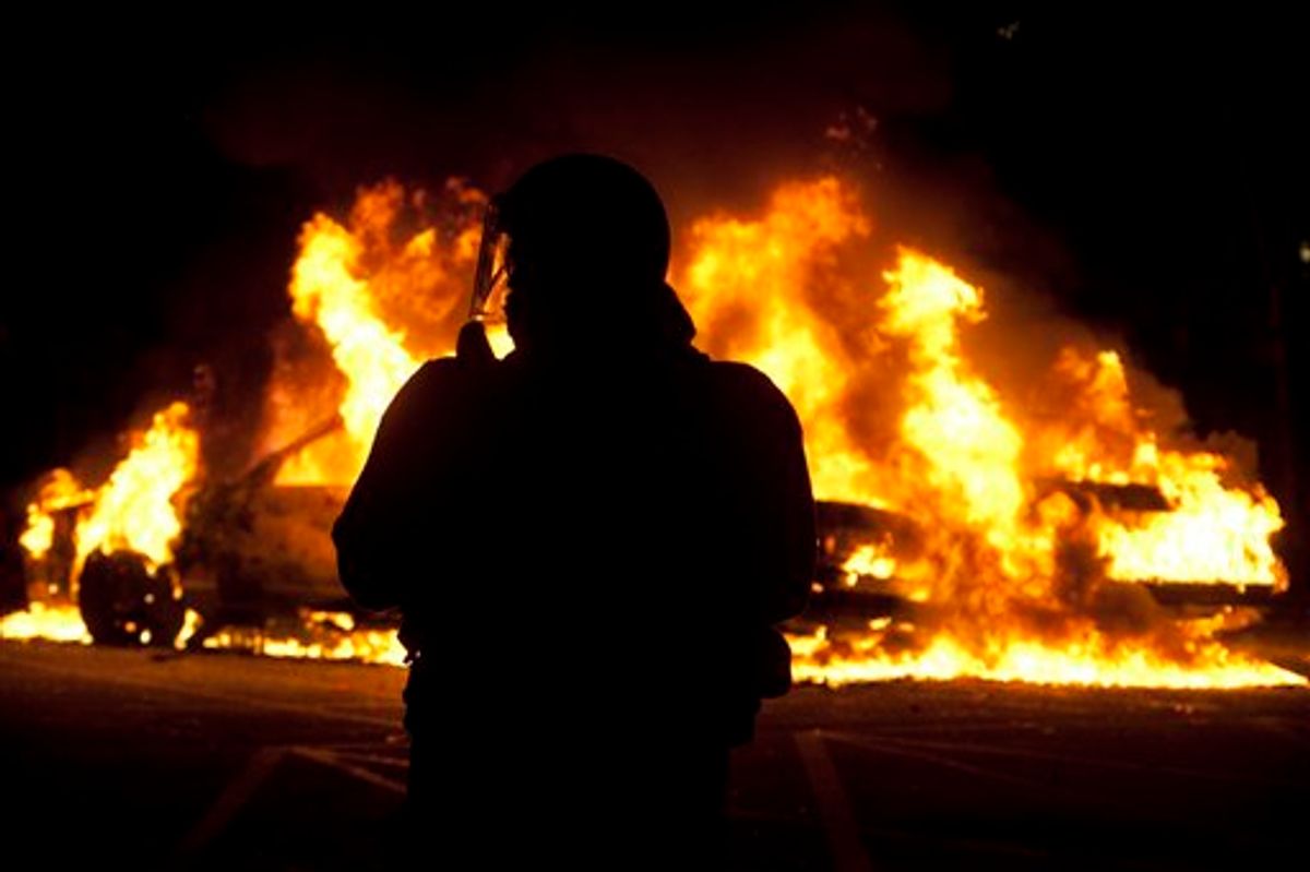 A riot officer watches as two police cars burn during a riot in downtown Vancouver, British Columbia Wednesday, June 15, 2011 following the Vancouver Canucks 4-0 loss to the Boston Bruins in game 7 of the Stanley Cup hockey final. Angry, drunken revelers ran wild Wednesday night after the Vancouver Canucks' 4-0 loss to Boston in Game 7 of the Stanley Cup finals, setting cars and garbage cans ablaze, smashing windows, showering giant TV screens with beer bottles and dancing atop overturned vehicles. (AP Photo/The Canadian Press, Jonathan Hayward) (AP)