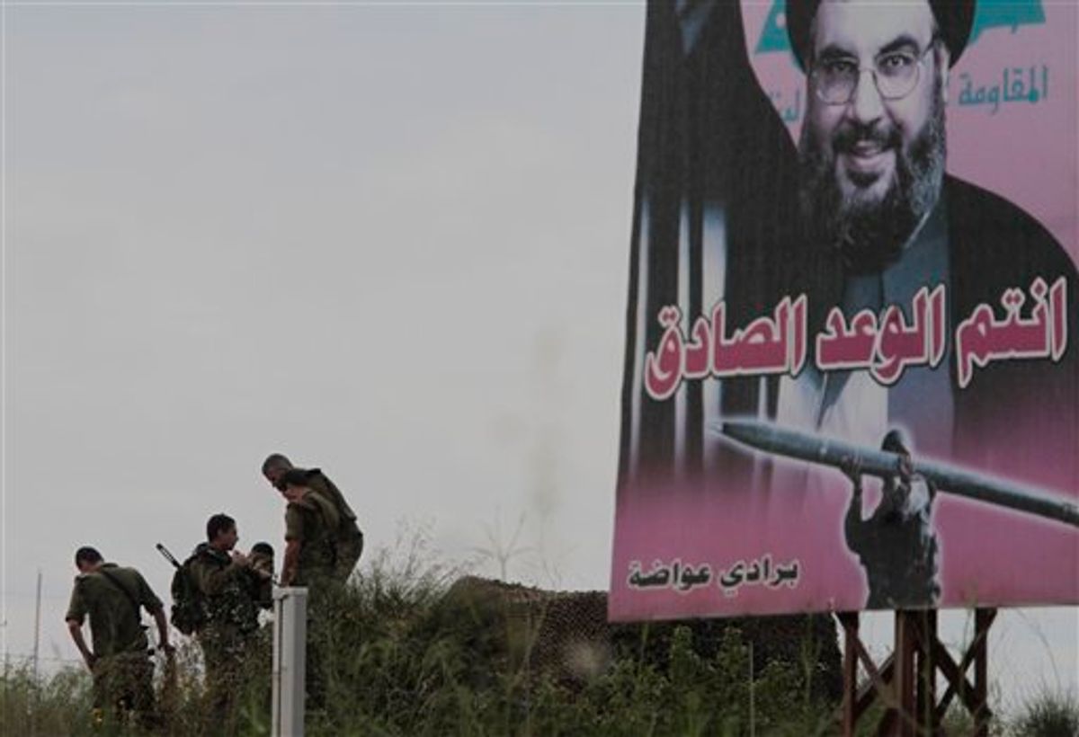 Israeli soldiers, left, take their position in the Israeli border side, as a poster of Hezbollah leader Hassan Nasrallah, right, is seen set at the Lebanese-Israeli border at Kfar Kila village, southern Lebanon, on Friday May 20, 2011. The Israeli army is beefing up its security apparently in anticipation of rallies of Palestinian refugees on the Lebanese-Israel border like the one the accured on Sunday. The Arbic words in the poster read:"you are the truthful pledge".(AP Photo/Mohammed Zaatari) (AP)