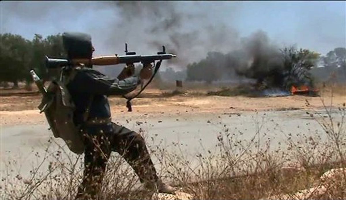 In this image taken from TV, showing rebel forces on the front line as they repel government troops, Sunday June 12, 2011, in Dafniya, Libya. as fighting continued on Sunday near Libya's main port of Misrata, a western redoubt of the rebels.  Video of the battle shows rebels advancing down a road, firing automatic weapons, guns mounted on pick up trucks, rockets and heavy artillery.  (AP Photo/APTN) TV OUT (AP)