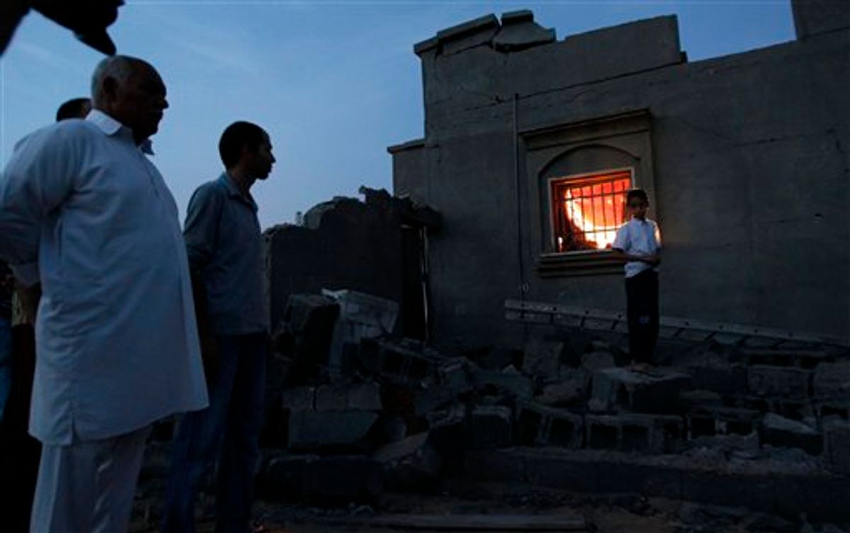 In this photo taken on a government organized tour, local residents stand next to a damaged house in Tripoli, Libya, on Sunday, June 5, 2011. Libyan officials claim that during a NATO airstrike, a rocket targeted a nearby military site hit a residential area and damaged several houses. (AP Photo/Ivan Sekretarev) (AP)