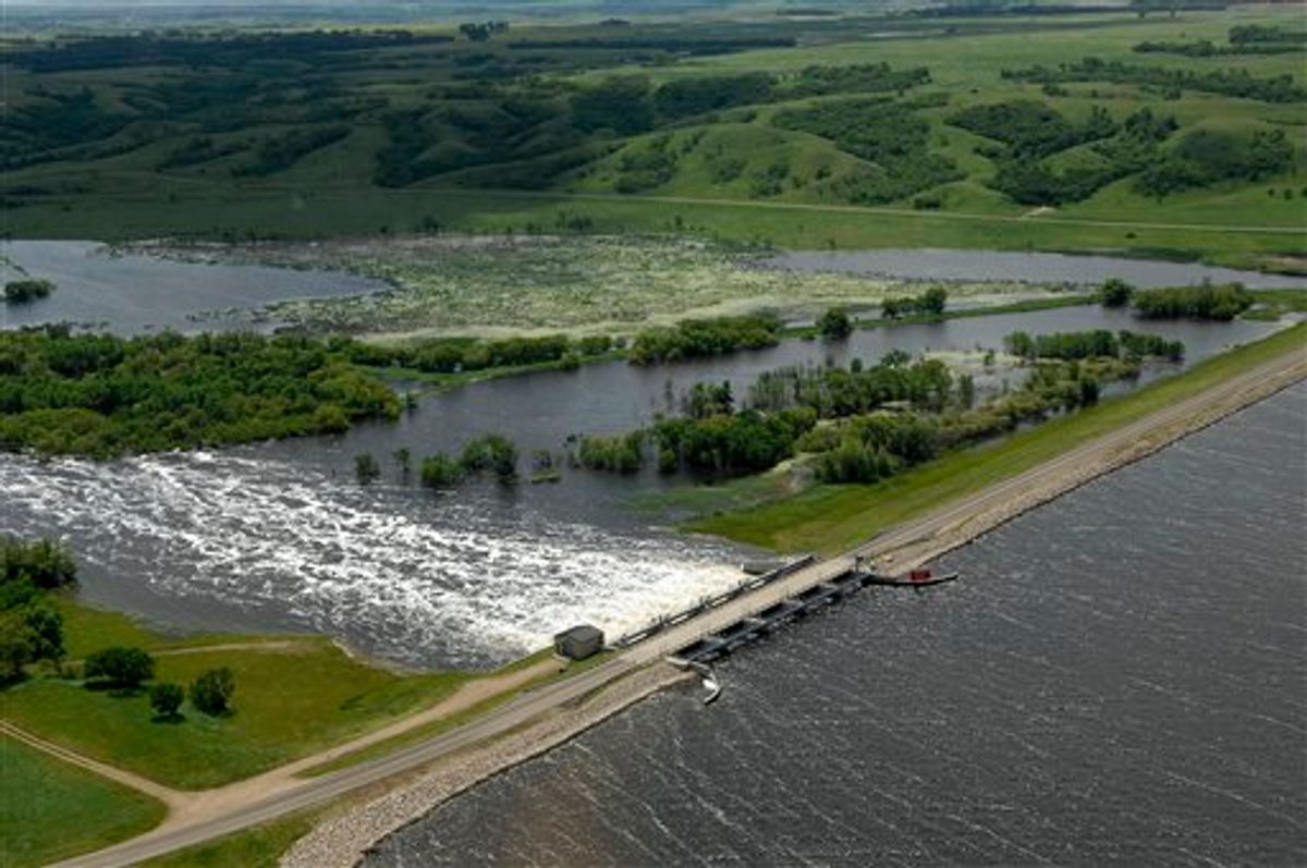 Water flows from Lake Darling into the Souris River on Wednesday, June 22, 2011. Lake Darling is located about fifteen miles north of Minot, ND.  As many as 10,000 people raced to evacuate Wednesday as water began spilling over Minot's levees. The river, which begins in the Canadian province of Saskatchewan and flows for a short distance though North Dakota, was all but certain to inundate thousands of homes and businesses during the next week. (AP Photo/Will Kincaid) (AP)