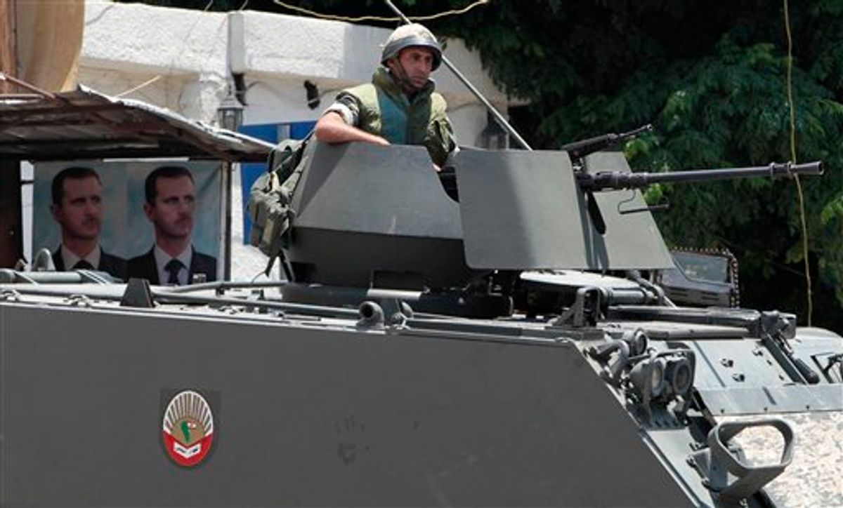 Lebanese army soldier, sits atop armored personnel carrier (APC), near to portraits of Syrian President Bashar Assad, on Saturday June 18 2011, on a street in Tripoli where a clashes broke between Sunni and Alawite groups on Friday, after a demonstration of the anti-Syrian regime protesters in Tripoli, northern Lebanon. A senior member of a Lebanese political party allied with Syria and an off-duty soldier were killed Friday after gunmen opened fire and lobbed a grenade near hundreds of people holding an anti-Assad protest in northern Lebanon, a security official said in Beirut. (AP Photo/Hussein Malla) (AP)