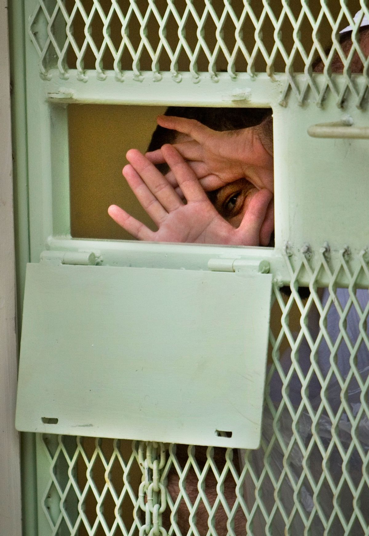 **FILE** In this Nov. 18, 2008 file photo, reviewed by the U.S. Military, a Guantanamo detainee peers through his hands from inside his cell at the Camp Echo detention facility at the U.S. Naval Base, in Guantanamo Bay, Cuba. A U.S. appeals court has overturned a ruling, Wednesday, Feb. 18, 2009, that would have transferred 17 Guantanamo Bay detainees to the United States. The men have been cleared for release from Guantanamo, but the United States will not send them home to China for fear they will be tortured. So they remain in prison while the U.S. figures out what to do with them. (AP Photo/Brennan Linsley, File) (Associated Press)