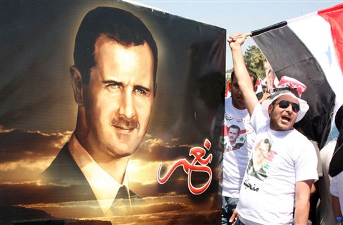 A Syrian shouts pro-Syrian President Bashar Assad slogans, as others carry a picture of Assad with writing in Arabic that reads:" Yes," during a rally in support of Assad, in Damascus, Syria, Tuesday, June 21, 2011. Tens of thousands of people waving flags and pictures of Assad converged on Syria's main squares Tuesday, pledging allegiance to their president in the latest show of government support to counter a three-month uprising against his authoritarian rule. (AP Photo/Bassem Tellawi) (AP)