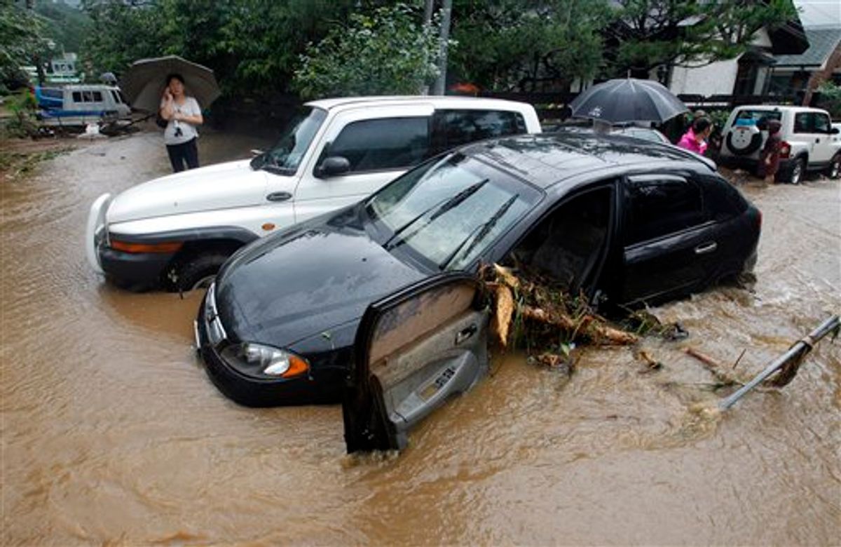 A resident uses her mobile phone near wrecked vehicles after a landslide caused by heavy rains in in Seoul, South Korea, Wednesday, July 27, 2011. A quick blast of heavy rain sent landslides barreling through South Korea's capital and a northern town Wednesday. (AP Photo/ Lee Jin-man) (AP)