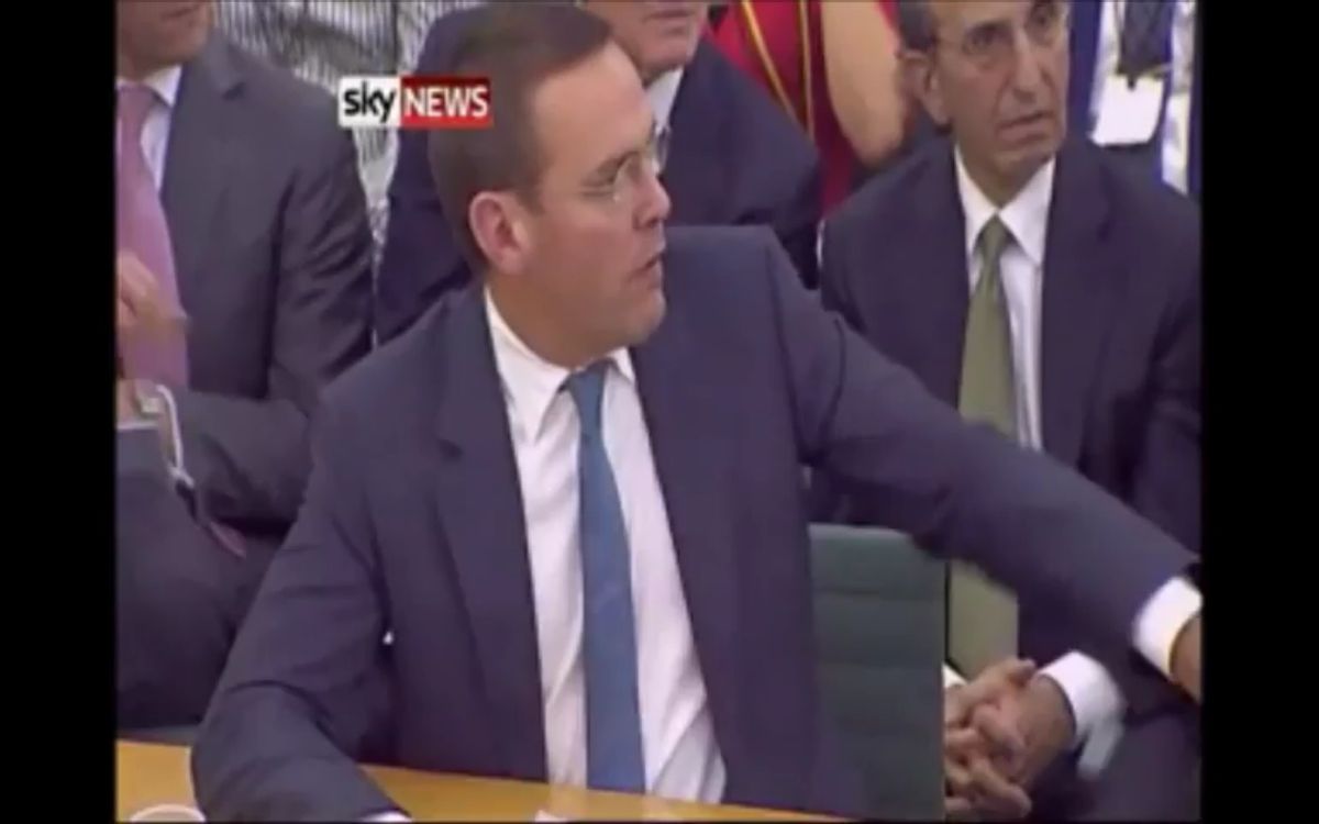 James Murdoch reacts with shock as an activist lunges towards his father Rupert with a cream pie 