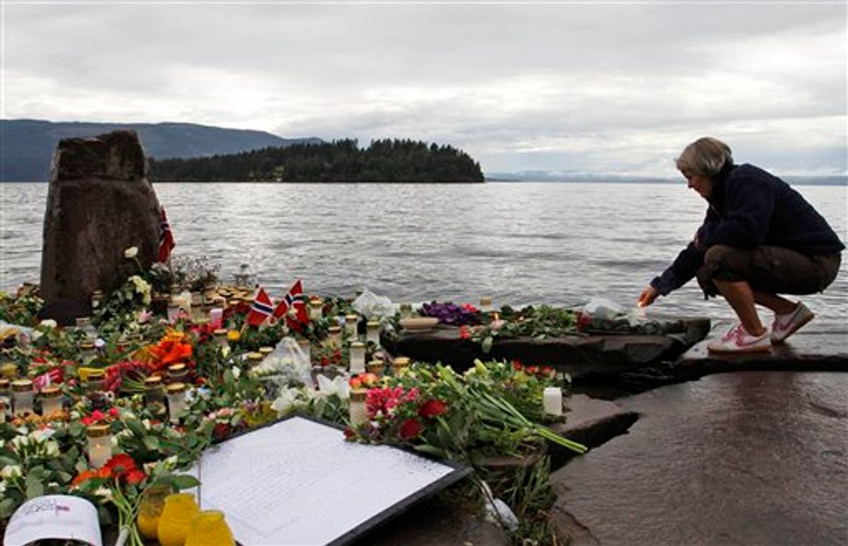 A woman lights a candle in Sundvollen, facing Utoya island, where gunman Anders Behring Breivik killed at least 68 people, near Oslo, Norway, Tuesday, July 26, 2011. Norwegian police on Tuesday began releasing the names of those killed in last week's bomb blast and massacre at a youth camp, an announcement likely to bring new collective grief to an already reeling nation. (AP Photo/Ferdinand Ostrop) (AP)