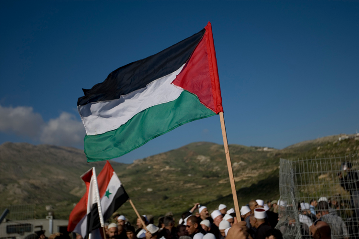 Druze men wave Palestinians and Syrian flags as they stand near the border fence between Israel and Syria on May 15, 2011
