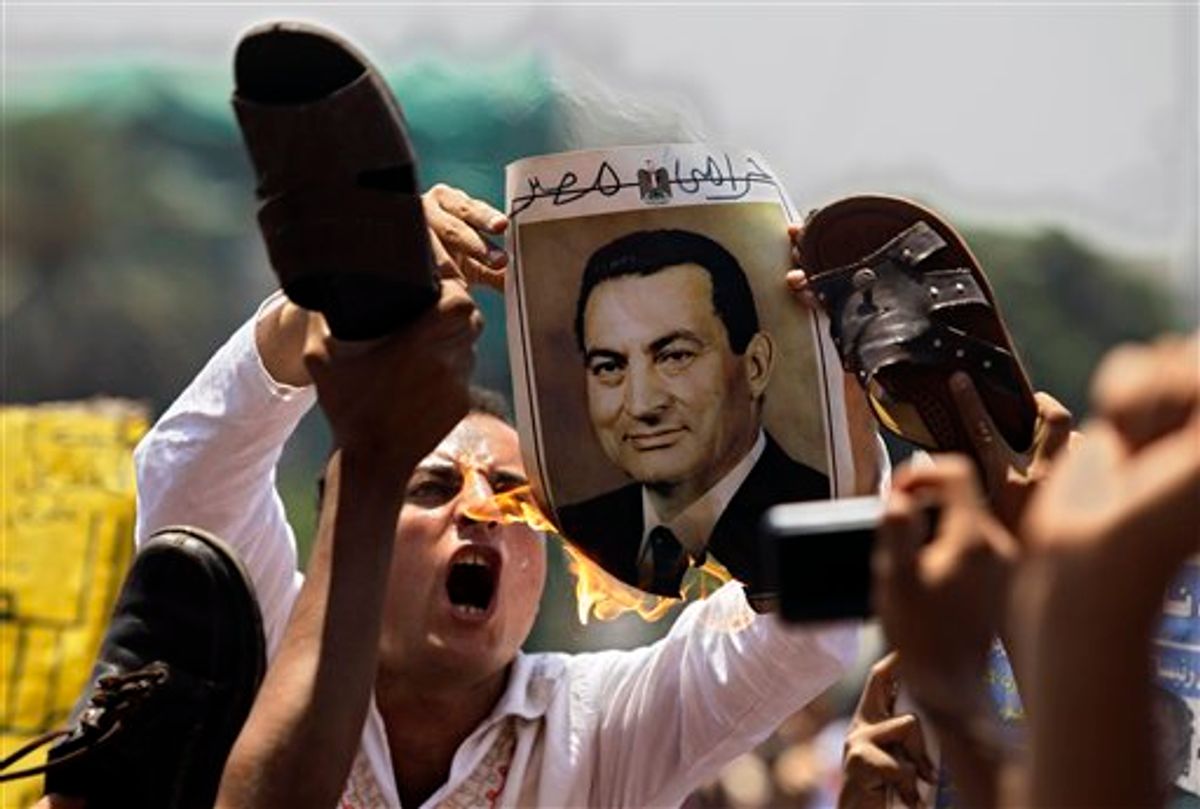 A man burns a picture of ousted Egyptian president Hosni Mubarak as others symbolically brandish a shoe at the image, their during a rally after Friday prayers in Tahrir Square, Cairo,  Friday, July 1, 2011.  (AP Photo/Sergey Ponomarev) (AP)