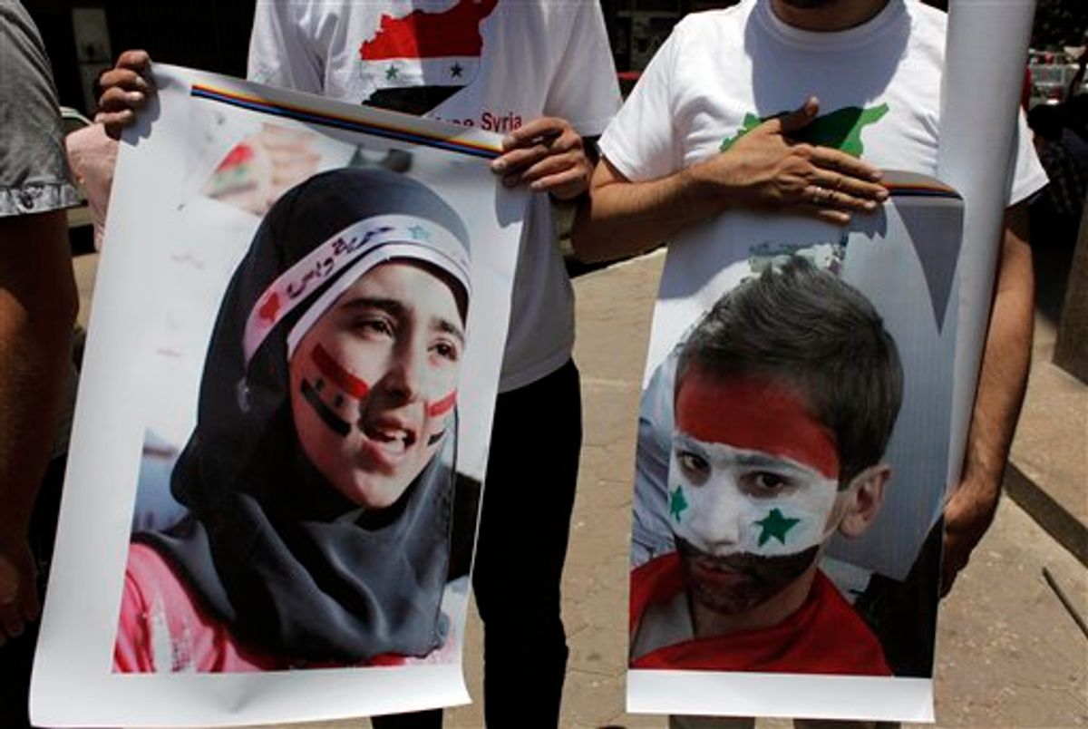Two protesters carry posters with pictures of unidentified relatives in Syria,  with the Syrian flag colors painted on their faces during an anti-Syrian regime rally near the Syrian embassy in Cairo, Egypt Tuesday, July 5, 2011. Syrian troops fired Tuesday on residents who set up makeshift roadblocks to prevent the advance of tanks ringing the city of Hama, which has become a flashpoint of the uprising against autocratic President Bashar Assad, activists said. (AP Photo/Nasser Nasser) (AP)