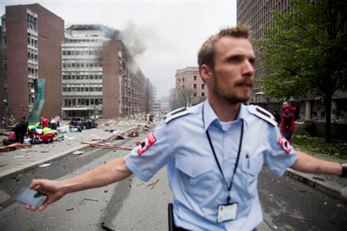 CORRECTS YEAR  An official attempts to clear away spectators from buildings in the centre of Oslo, Friday July 22, 2011, following an explosion that tore open several buildings including the prime minister's office, shattering windows and covering the street with documents.(AP Photo/Fartein Rudjord) NORWAY OUT: (AP)