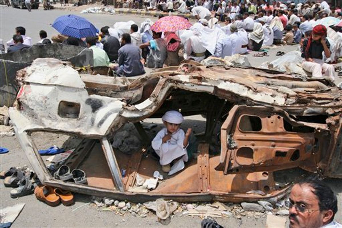 A Yemeni boy sits inside a wreckage of a car while anti-government protestors, attend Friday prayers, during a demonstration demanding the resignation of Yemeni President Ali Abduallah Saleh, in Taiz, Yemen, Friday, July 15, 2011. Tribesmen killed a Yemeni army officer and two of his aides in an ambush Friday, and government shelling killed two civilians in a volatile southern area, officials said. (AP Photo/Anees Mahyoub) (AP)