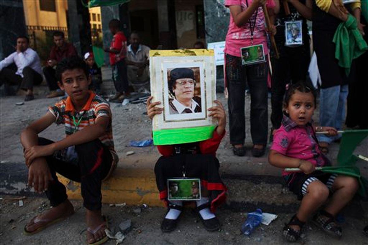 In this photo taken on a government-organized tour, a child rests as she holds up a picture of LIbyan leader Moammar Gadhafi during a rally in the town of Zawiya, roughly 50 km (30 miles) west of Tripoli, Libya, Saturday, July 16, 2011. Ten rebel fighters were killed in an advance on the strategic oil town of Brega in eastern Libya on Saturday, with rebel forces sweeping the outskirts for land mines so they could move in, officials said. The advance came after Libya's main opposition group was recognized by more than 30 nations, including the U.S., as Libya's legitimate government. Friday's decision potentially frees up billions of dollars in cash that the rebels urgently need. (AP Photo/Tara Todras-Whitehill) (AP)