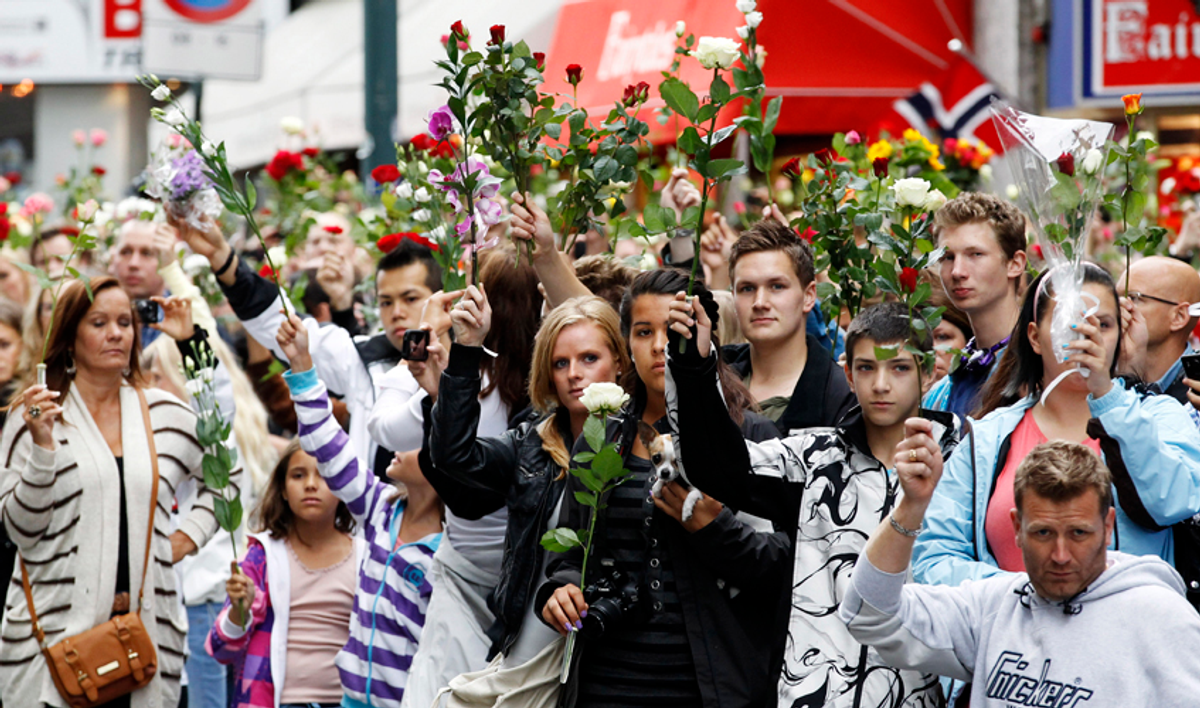 People hold up flowers as they take part in a memorial march for the victims of the killing spree and bomb blast in downtown Oslo