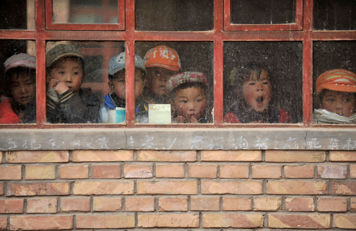 Children look out from a window of their classroom at a rural primary school in Min county, Gansu province June 1, 2011   