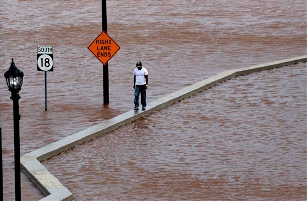 A man walks on top of a wall next  to a flooded highway in New Brunswick, N.J.,  Aug. 28, 2011, as heavy rains left by Hurricane Irene are causing inland flooding of rivers and streams.  Flood waters rose all across New Jersey on Sunday, closing roads from side streets to major highways as Hurricane Irene weakened and moved on, leaving 600,000 homes and businesses without power. (AP Photo/Mel Evans) (AP)
