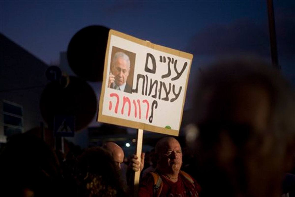 An Israeli man holds a sign reading " Eyes shut wide" with a portrait of Prime Minister Benjamin Netanyahu during a protest in Tel Aviv, Israel, Saturday, Aug. 6, 2011.   