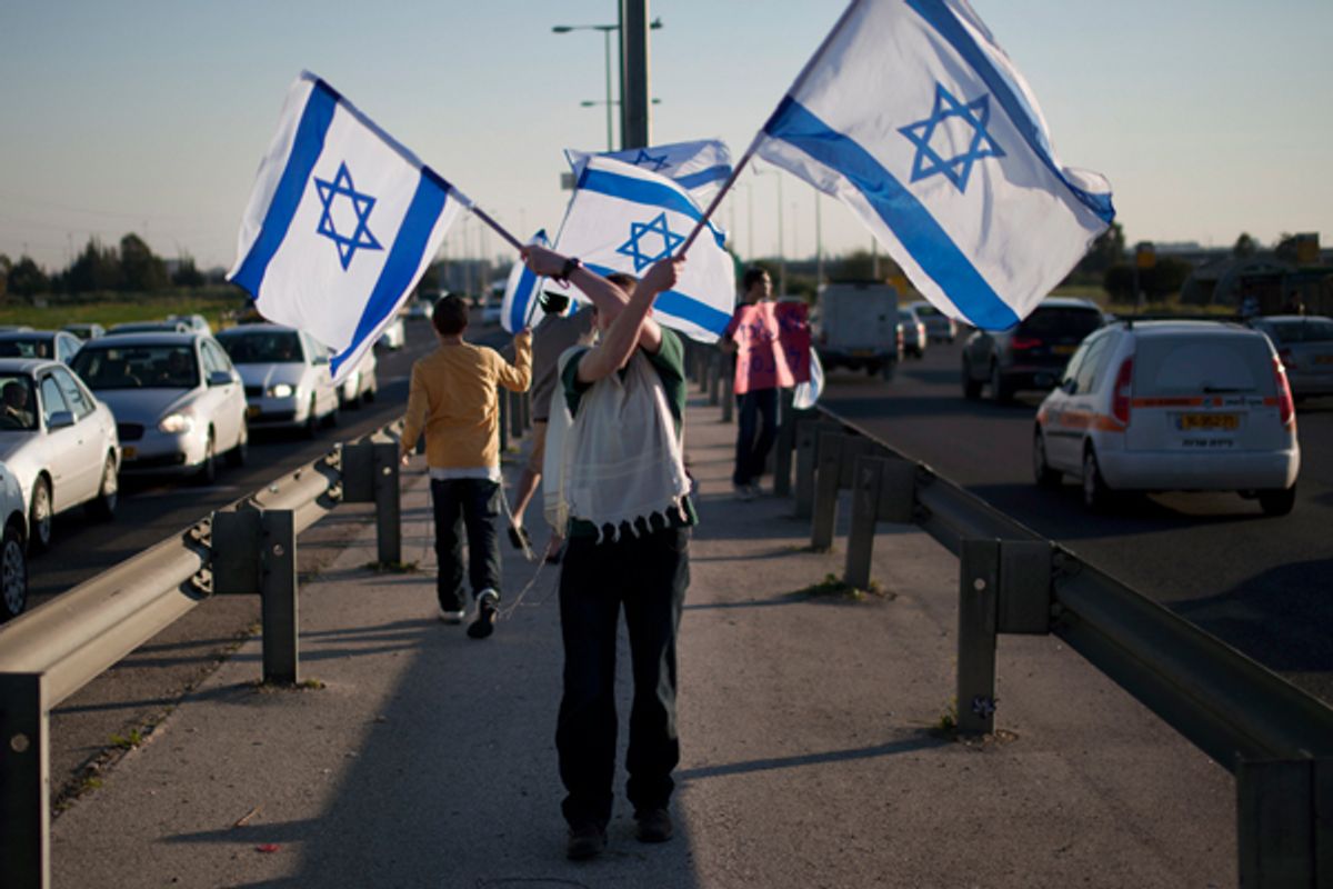A Jewish settler holds Israeli flags as he protests in support of the Jewish settlers in the West Bank.
