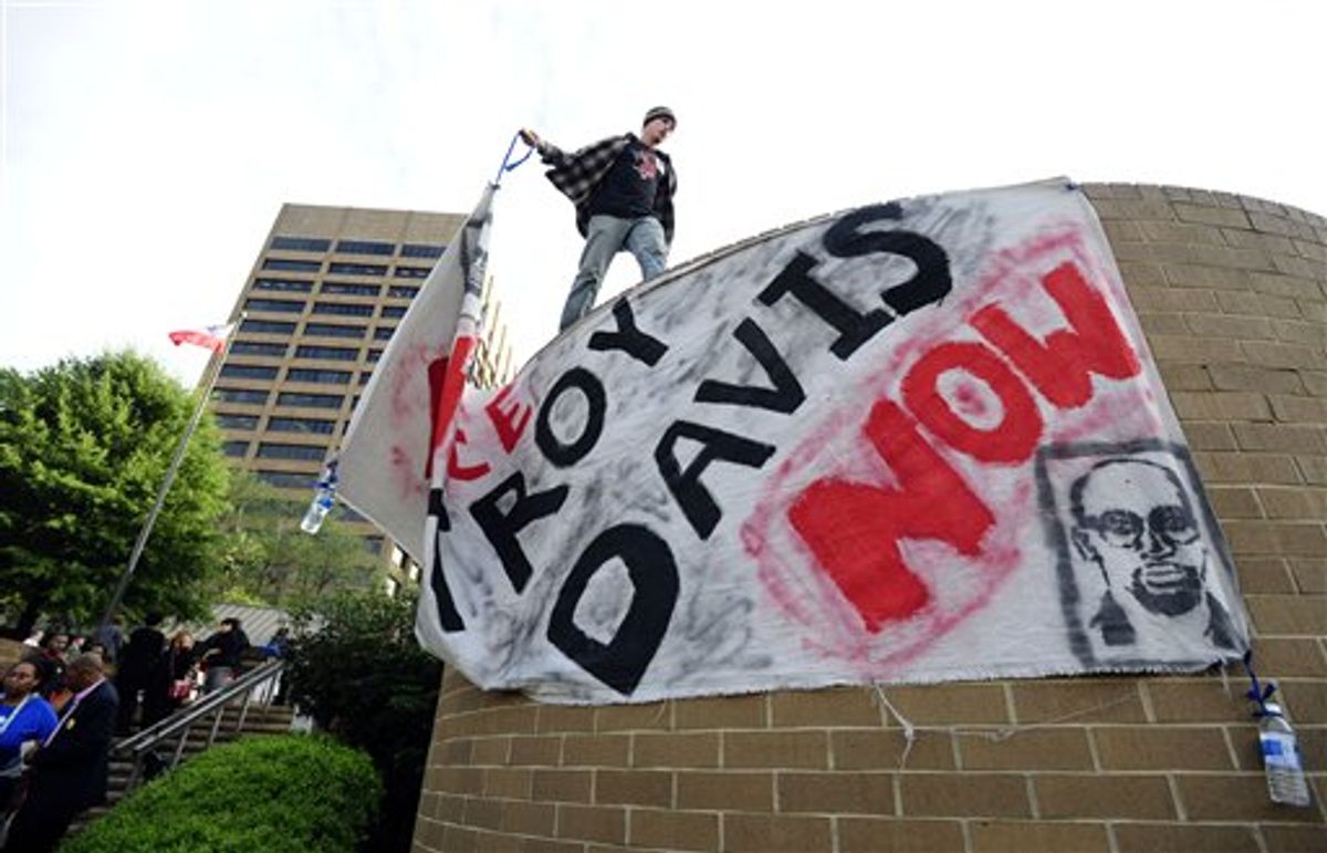 Protester Jason Ebinger removes a sign from outside the building where members of the Georgia Board of Pardons and Paroles are meeting to hear the case of death row inmate Troy Davis, Monday, Sept. 19, 2011, in Atlanta. Davis is scheduled to be executed on Wednesday, Sept. 21, 2011, for the 1989 murder of off-duty Savannah police officer Mark MacPhail. (AP Photo/David Tulis) (AP)