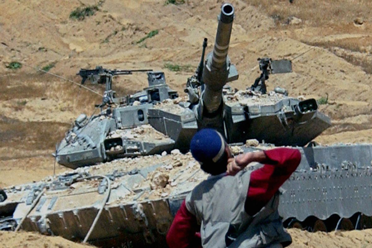 A Palestinian youth throws rocks towards a tank during clashes with Israeli soldiers