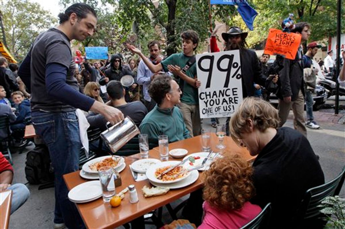 A demonstrator affiliated with the Occupy Wall Street march past a family dining at an outdoor restaurant, Saturday.     (AP/Mary Altaffer)