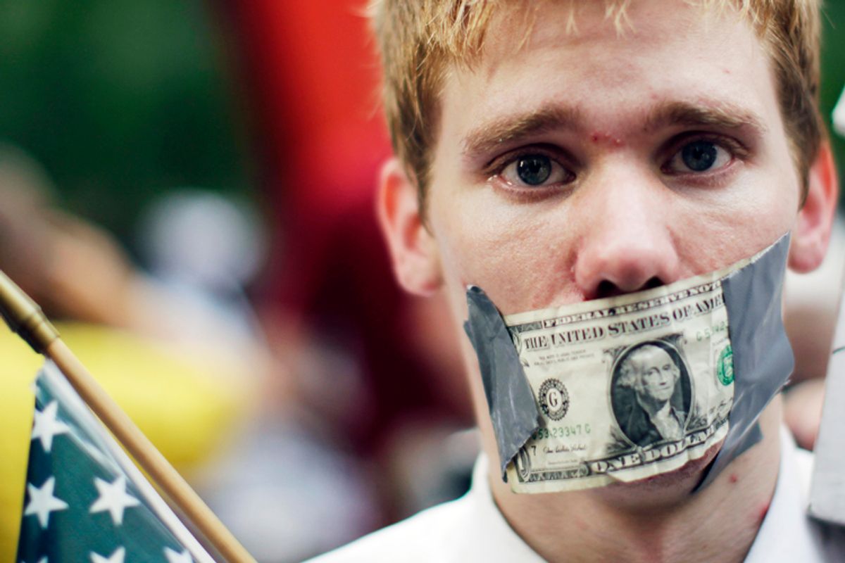 A demonstrator from the Occupy Wall Street campaign stands with a dollar taped over his mouth as he stands in Zucotti Park near the financial district of New York September 30, 2011.         (Lucas Jackson / Reuters)
