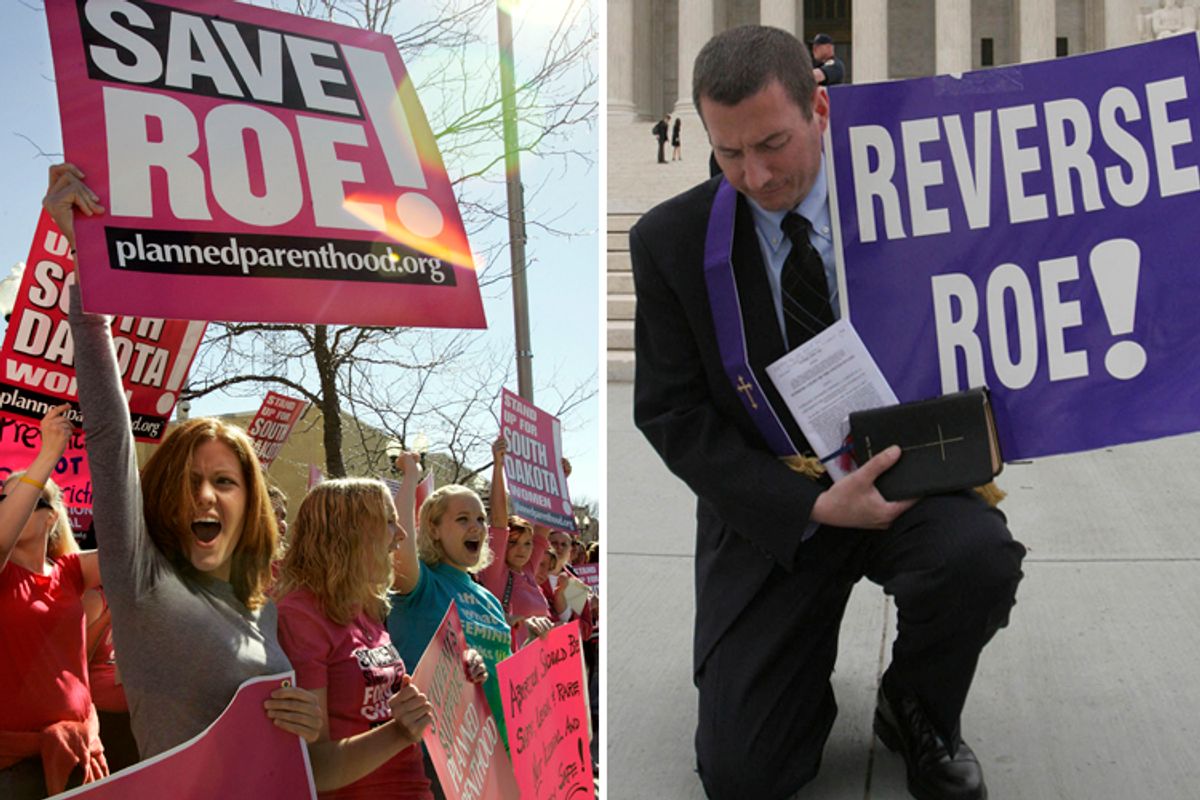 Demonstrators protest South Dakota's abortion ban. Right: National Clergy Council president Rev. Rob Schenck holds a one-man counter protest, as abortion rights demonstrators gather outside the Supreme Court in Washington, April 18, 2007.   (AP)