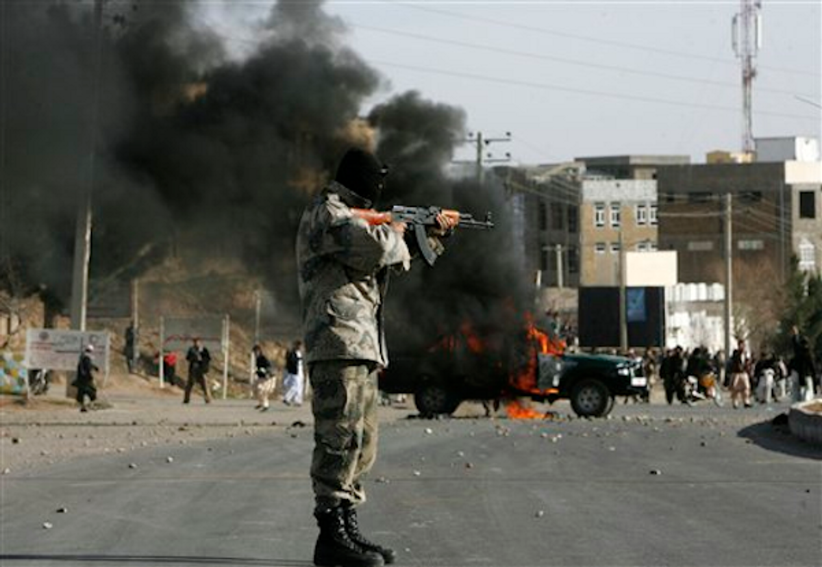 Afghan policeman aims at protesters by a burning police truck set alight during an anti-U.S. demonstration over burning of Qurans at a U.S. military base in Afghanistan, in Herat, Friday, Feb. 24, 2012.     (AP Photo/Hoshang Hashim)