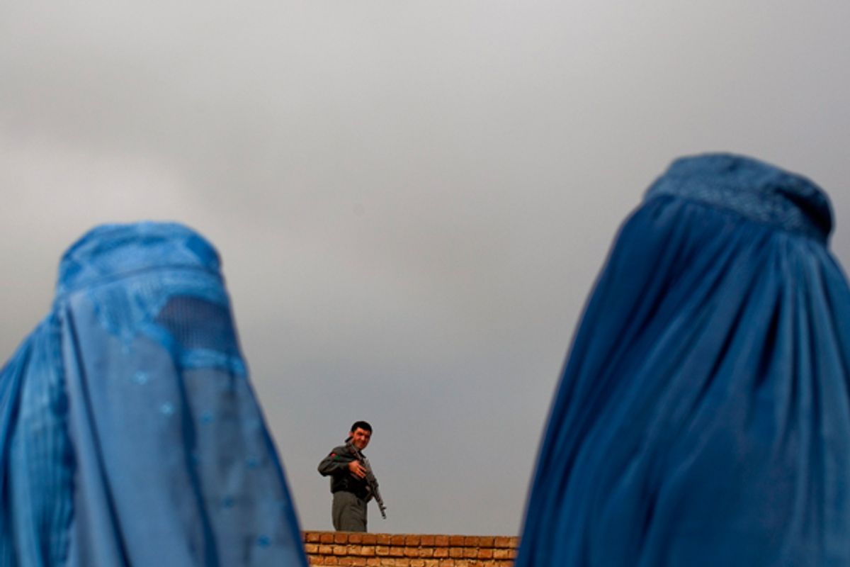 Women line up as a policeman keeps watch during the distribution of winter assistance in Kabul.    (Reuters/Ahmad Masood)