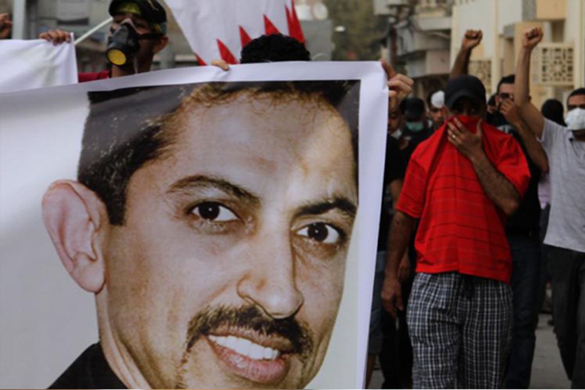 Bahraini anti-government protesters, protecting their faces from tear gas, carry national flags and a picture of jailed human rights activist Abdulhadi al-Khawaja at a protest on ApPril 4.     (AP/Hasan Jamali)