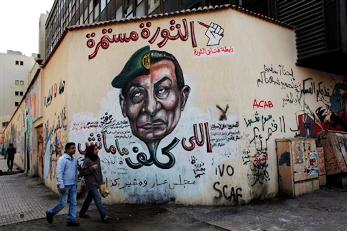 In this Thursday, March 22, 2012 photo, an Egyptian couple walks past a mural depicting military ruler Field Marshal Hussein Tantawi, on the left side of the face and ousted president Hosni Mubarak, right side, in Cairo, Egypt        (AP Photo/Nasser Nasser)