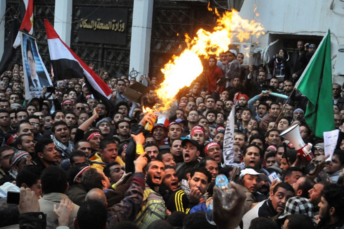 Egyptian protesters, left, spray burning aerosol over Muslim Brotherhood guards outside the Egyptian parliament.      (AP)