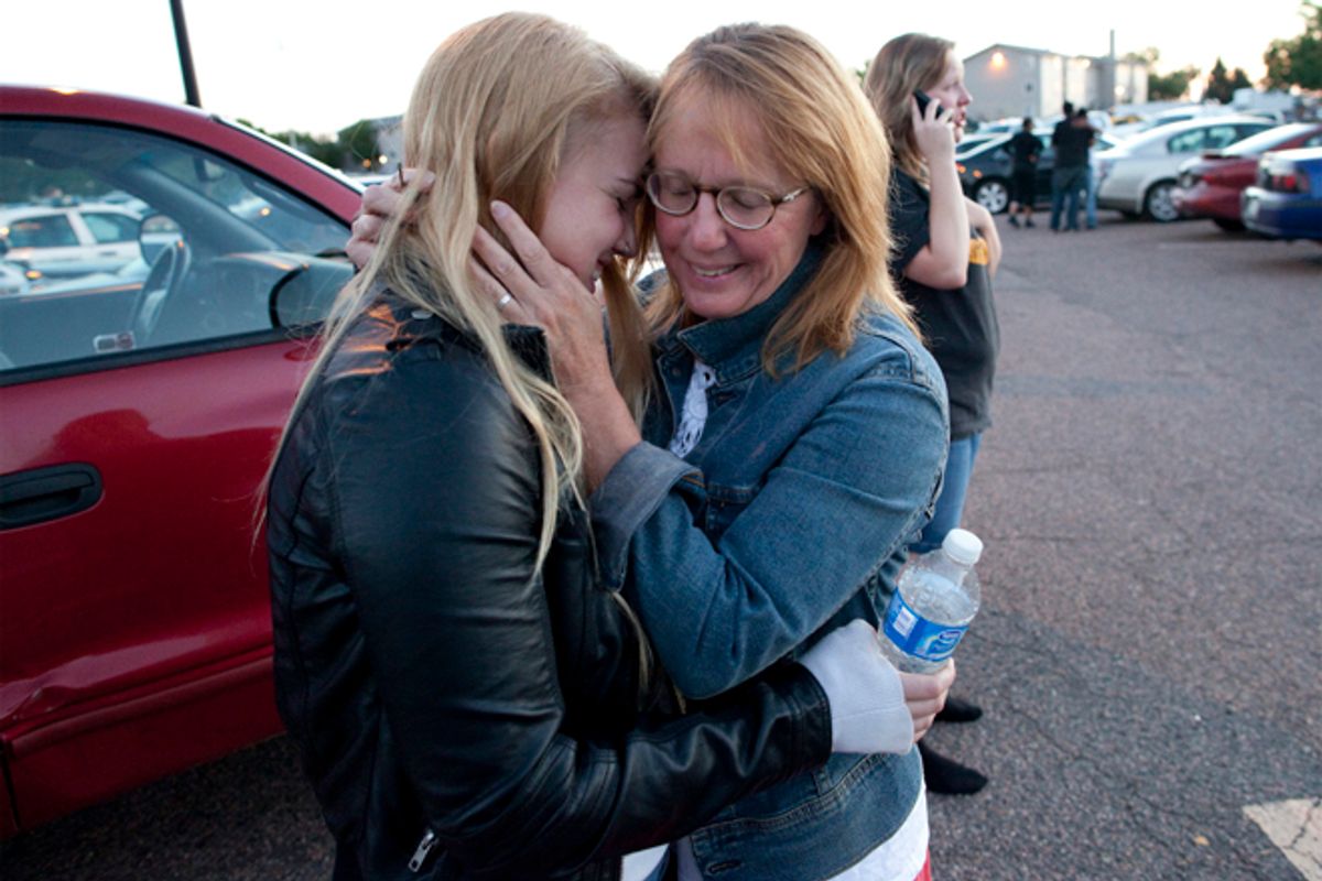 Emma Goos, 19, hugs her mother, Judy Goos, outside Gateway High School where witnesses were brought for questioning Friday, July 20, 2012, in Aurora, Colo. Emma was in the third row of the theater of the new Batman movie when the shooter entered. She helped apply pressure to a man's head who was injured. (AP Photo/Barry Gutierrez)       (AP/Barry Gutierrez)