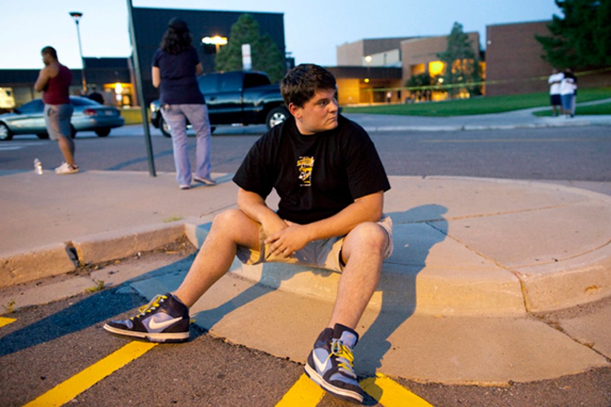 Eyewitness Chandler Brannon, 25, sits outside Gateway High School where witnesses were brought for questioning after a shooting at a movie theater showing the Batman movie "The Dark Knight Rises," Friday, July 20, 2012 in Aurora.  A gunman wearing a gas mask set off an unknown gas and fired into the crowded movie theater killing 12 people and injuring at least 50 others, authorities said. (AP Photo/Barry Gutierrez)     (AP/Barry Gutierrez)