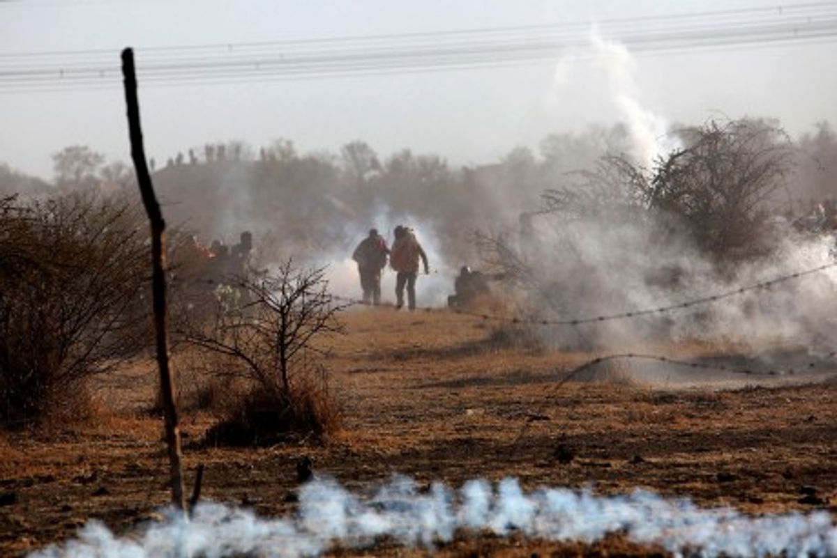  Striking mineworkers are caught in teargas as police open fire on striking miners at the Lonmin Platinum Mine near Rustenburg, South Africa, Thursday, Aug. 16, 2012. An unknown number of people have been killed and injured. Police moved in on workers who gathered on a rocky outcropping near the Lonmin late afternoon, firing unknown ammunition and teargas. (AP Photo) SOUTH AFRICA OUT(Credit: AP) 