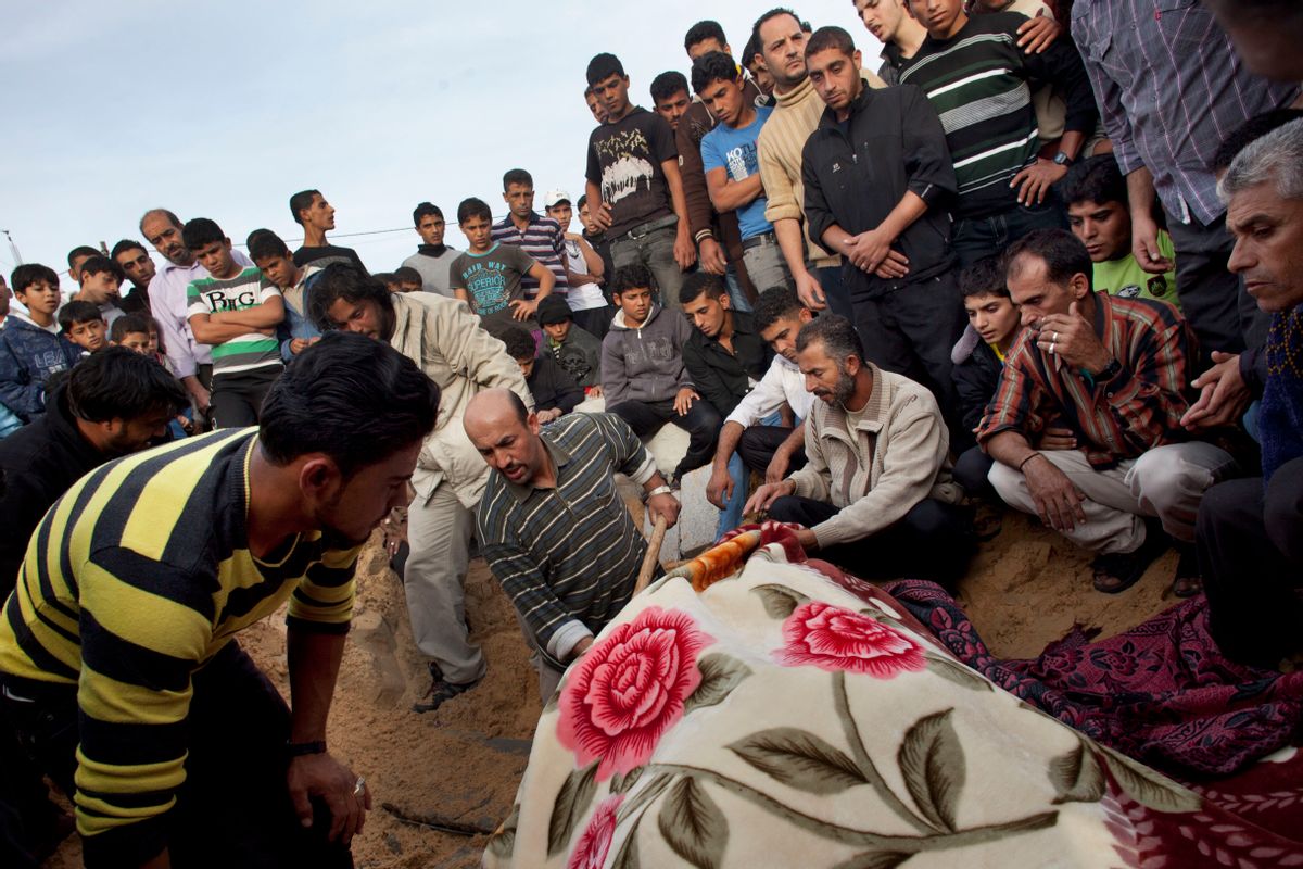 Palestinians bury the body of Tahrer Salman, covered with a blanket, during her funeral in Beit Lahia, north Gaza, Friday, Nov. 16, 2012.  According to relatives, Tahrer Salman and Mohammed Salman were killed after an Israeli airstrike hit the yard of their house.        (AP/Bernat Armangue)
