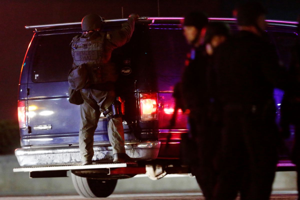 A police officers rides on the back of a van at a staging area as a manhunt is conducted for a suspect Friday, April 19, 2013, in Watertown, Mass.    (AP/Matt Rourke)