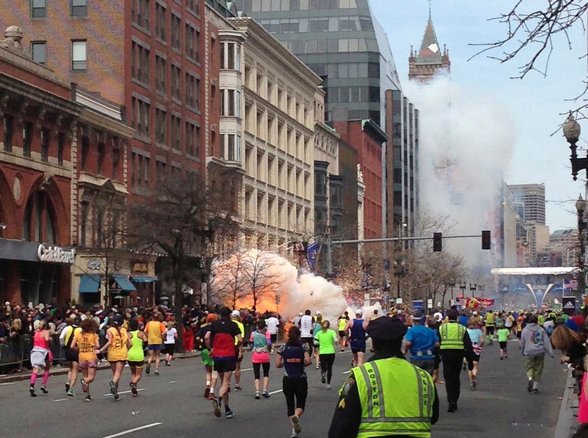 Runners continue to run towards the finish line of the Boston Marathon as an explosion erupts near the finish line.    (Reuters/Dan Lampariello)