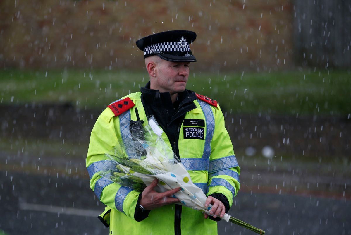A police officer holds a floral tribute handed to him by a member of the public to be placed at the scene of a terror attack in Woolwich, southeast London, Thursday, May 23, 2013.   (AP/Sang Tan)