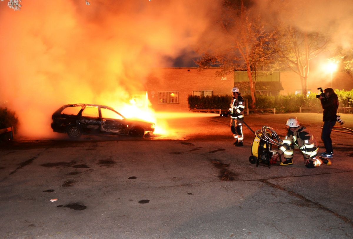Firefighters extinguish a burning car, following riots in the Stockholm suburb of Kista late May 21, 2013.    (Reuters/Fredrik Sandberg/Scanpix)