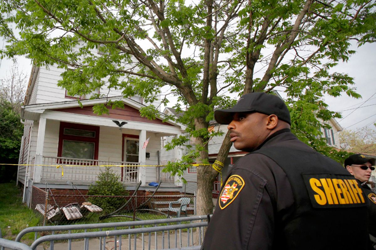 A sheriff deputy stands outside the Cleveland house where Amanda Berry, Gina DeJesus and Michelle Knight were allegedly held captive for almost a decade.           (AP/Tony Dejak)