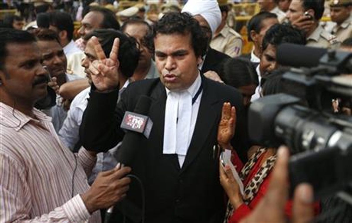 An unidentified lawyer from the prosecution side displays a victory sign as he speaks to journalists after a judge pronounced death sentence for all four men convicted in the rape and murder of a student on a moving New Delhi bus last year, in New Delhi, India, Friday, Sept. 13, 2013. The judge on Friday ordered all four to the gallows for a brutal attack on a bus that left the young woman with such severe internal injuries that she died two weeks later.  (AP Photo/Saurabh Das)
