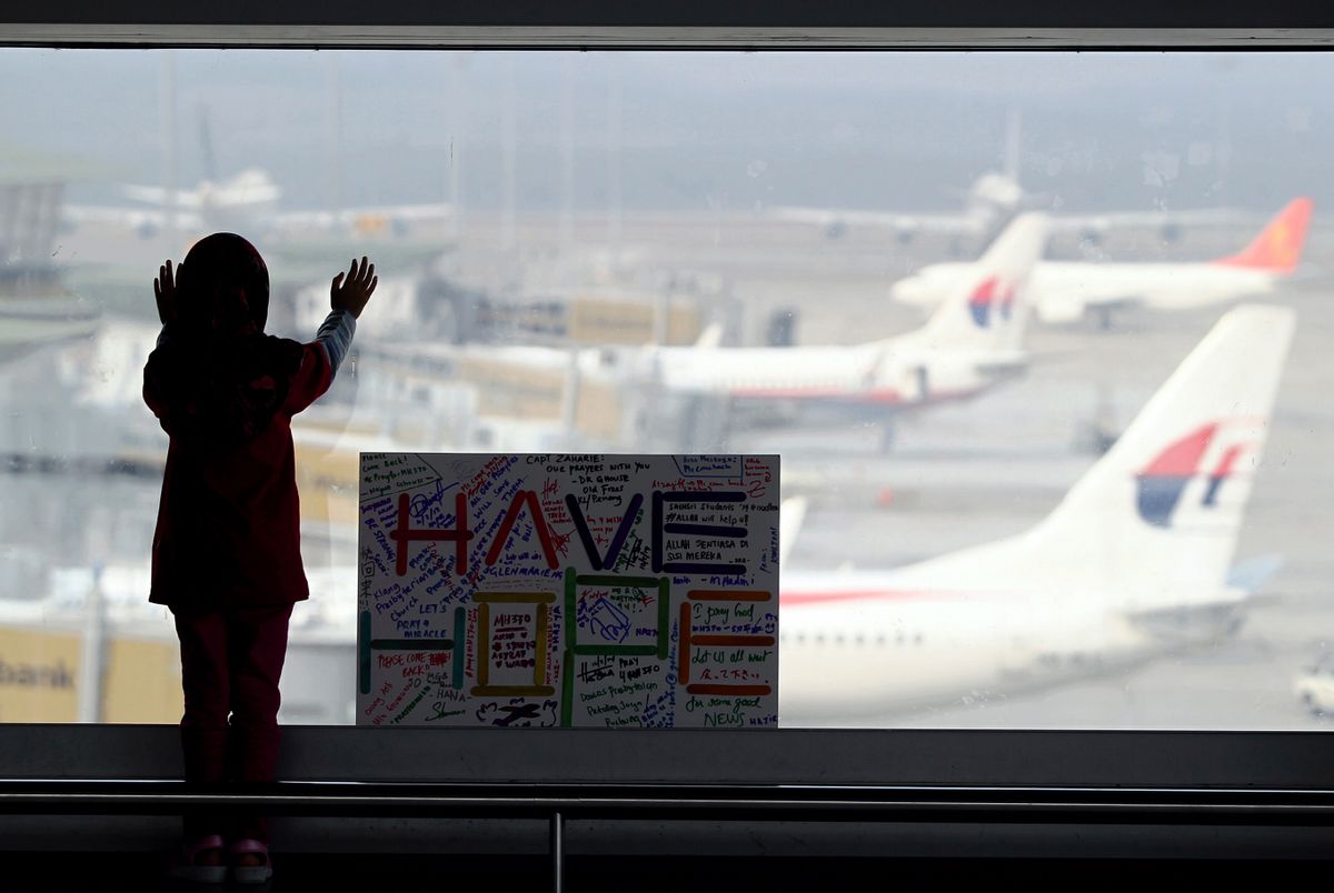 A girl stands next to a cardboard reading "Have Hope" written by the public at Kuala Lumpur International Airport in Sepang, Malaysia, Monday (Daniel Chan)